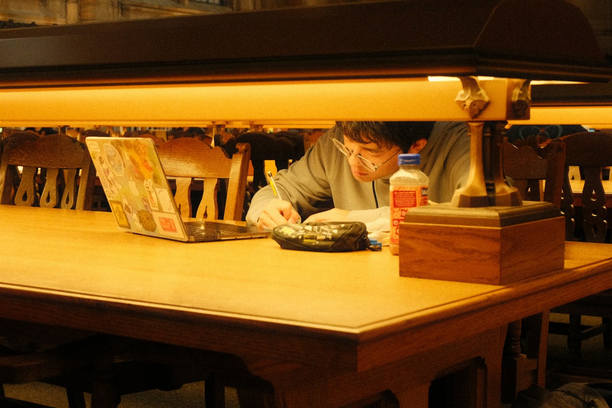 Focused student studying thesis material at a library table